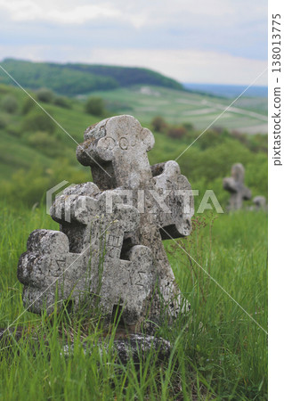 Two ancient weathered stone crosses with Cyrillic inscriptions standing on a green hillside in Ukraine Two ancient weathered stone crosses with Cyrillic inscriptions standing on a green hillside in Ukraine 138013775