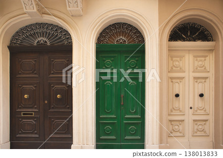 Three colorful traditional wooden doors with ornate ironwork in an arched facade 138013833