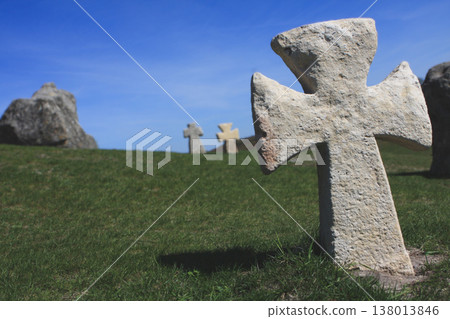 Ancient stone Cossack cross standing on a grassy hill under a bright blue summer sky 138013846