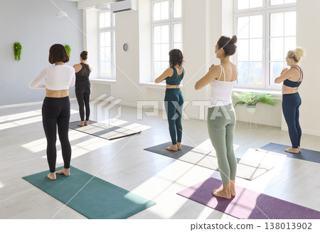 Yoga class in mountain pose with prayer hands inside bright, airy studio Yoga class in mountain pose with prayer hands inside bright, airy studio 138013902