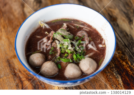 Traditional Thai boat noodles with beef slices meatballs herbs and rich dark broth served in bowl highlighting authentic street food flavor and comforting asian cuisine Traditional Thai boat noodles with beef slices meatballs herbs and rich dark broth served in bowl highlighting authentic street food flavor and comforting asian cuisine 138014129