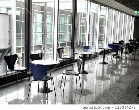 The interior of an airport terminal with panoramic windows and a seating area The interior of an airport terminal with panoramic windows and a seating area 138014272