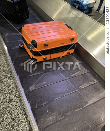 A bright orange suitcase on the baggage claim belt at the airport 138014284