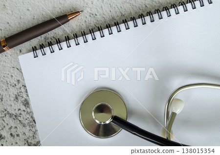 Simple notebook flat lay with a pencil and doctor stethoscope on a soft textured surface, with customizable space on notebook for text or ideas 138015354
