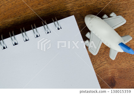 Top view of blank spiral notebook on a wooden desk beside toy airplane Top view of blank spiral notebook on a wooden desk beside toy airplane 138015359