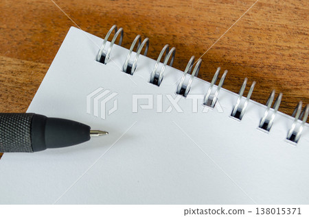 White spiral notebook on wooden desk with black pen and copy space, with customizable space on notebook for text or ideas 138015371