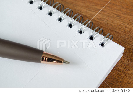Blank spiral notebook on a wooden desk with a sharpened pencil and ample copy space, with customizable space on notebook for text or ideas 138015380