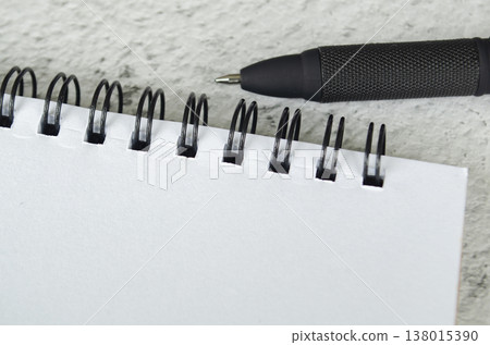 Blank spiral notebook composition with black pen on light textured background, with customizable space on notebook for text or ideas 138015390
