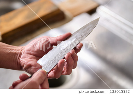 A man tests the sharpness of a kitchen knife. 138015522