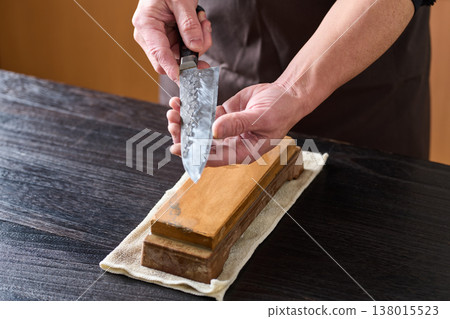 A man tests the sharpness of a kitchen knife. 138015523