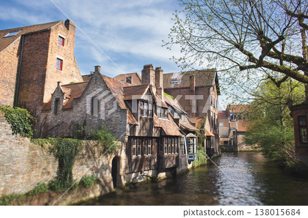 Quaint medieval timber-framed house and historic brick buildings along a narrow canal in Bruges, Belgium 138015684