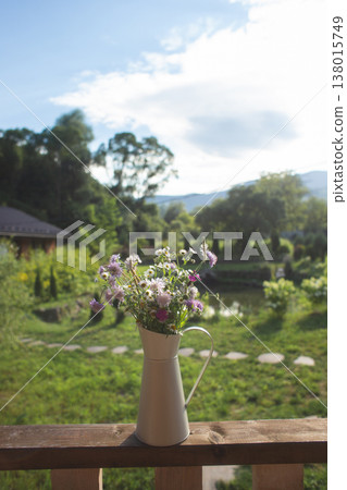 Wildflower bouquet in a rustic pitcher on a balcony overlooking a garden Wildflower bouquet in a rustic pitcher on a balcony overlooking a garden 138015749