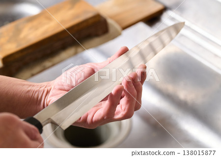 一名男子正在測試一把廚房刀的鋒利度。 138015877