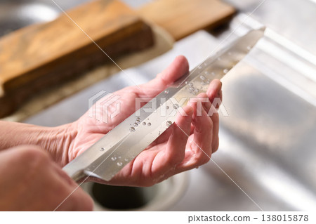 A man tests the sharpness of a kitchen knife. 138015878