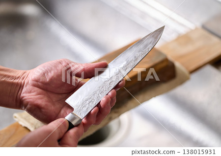 A man tests the sharpness of a kitchen knife. 138015931