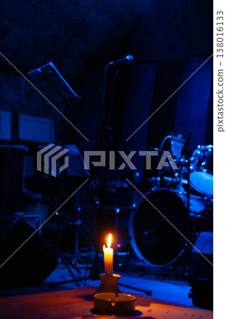 a drum set in blue light and a brightly lit candle a drum set in blue light and a brightly lit candle 138016133