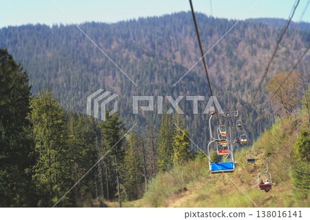Colorful chairlift cabins moving over a green forest valley in the Carpathian Mountains Colorful chairlift cabins moving over a green forest valley in the Carpathian Mountains 138016141