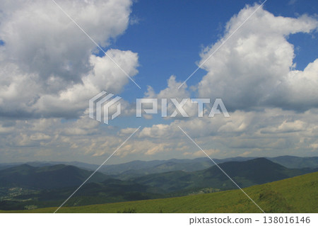 Scenic panoramic view of rolling green mountain ridges under a blue sky with white clouds Scenic panoramic view of rolling green mountain ridges under a blue sky with white clouds 138016146