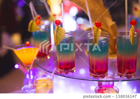 Vibrant layered cocktails with fruit garnishes at a night event Vibrant layered cocktails with fruit garnishes at a night event 138016147