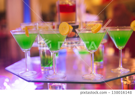 Vibrant green martini cocktails on a glass display at a festive event Vibrant green martini cocktails on a glass display at a festive event 138016148