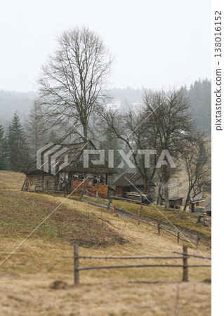Rustic wooden cabin on a mountain slope in late autumn or winter 138016152