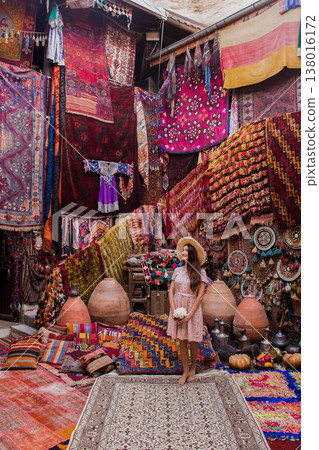 a beautiful girl in dress in a traditional turkish interior with many carpets on the wall 138016172