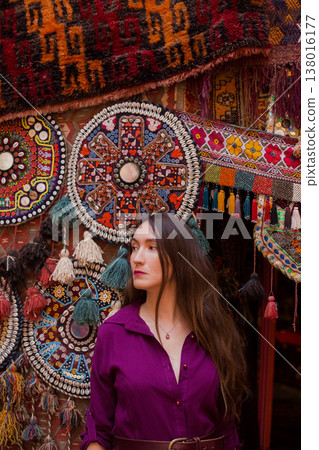 a beautiful girl in dress in a traditional turkish interior with many carpets on the wall a beautiful girl in dress in a traditional turkish interior with many carpets on the wall 138016177