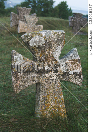 Ancient stone Cossack cross standing on a grassy hill under a bright blue summer sky 138016187