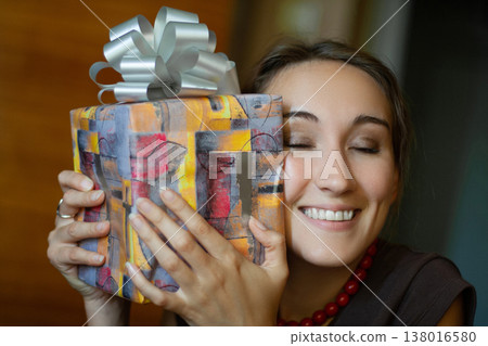 Surprised and happy woman holding a beautifully wrapped gift Surprised and happy woman holding a beautifully wrapped gift 138016580