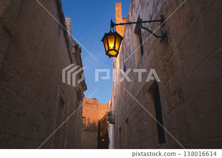 Vintage wrought iron lantern in a narrow Mdina street at twilight 138016614