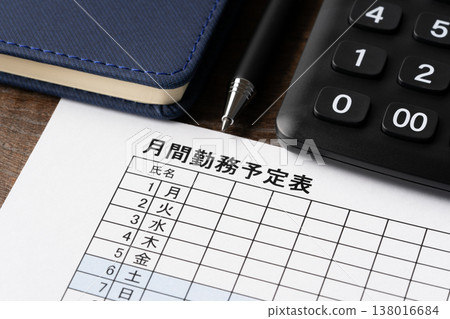 A close-up of a monthly work schedule, ballpoint pen, notebook, and calculator. A close-up of a monthly work schedule, ballpoint pen, notebook, and calculator. 138016684