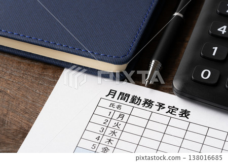 A close-up of a monthly work schedule, ballpoint pen, notebook, and calculator. A close-up of a monthly work schedule, ballpoint pen, notebook, and calculator. 138016685