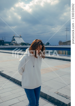 A smiling woman in her 20s walking through the streets of a tourist town. A smiling woman in her 20s walking through the streets of a tourist town. 138016692