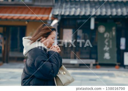 A smiling woman in her 20s walking through the streets of a tourist town. A smiling woman in her 20s walking through the streets of a tourist town. 138016700
