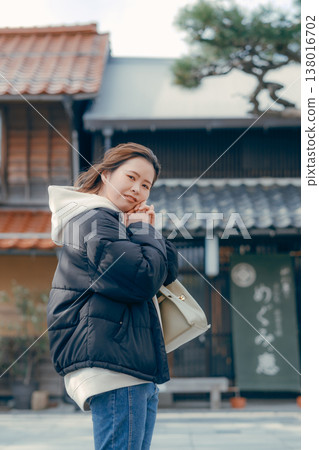 一位二十多歲、微笑的女子走在旅遊小鎮的街道上。 138016702