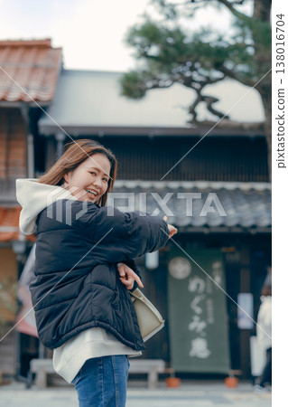 一位二十多歲、微笑的女子走在旅遊小鎮的街道上。 一位二十多歲、微笑的女子走在旅遊小鎮的街道上。 138016704