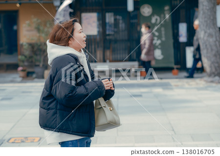 一位二十多歲、微笑的女子走在旅遊小鎮的街道上。 138016705