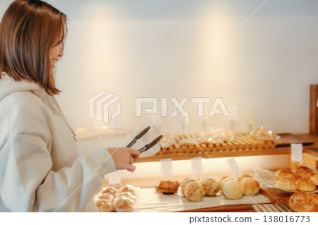 A woman in her 20s, seen from behind, choosing bread at a bakery. 138016773