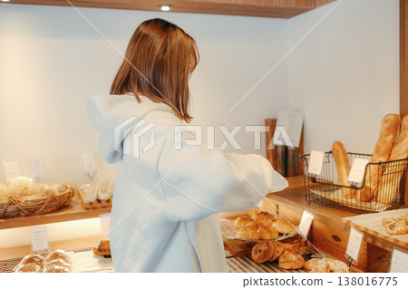 A woman in her 20s, seen from behind, choosing bread at a bakery. A woman in her 20s, seen from behind, choosing bread at a bakery. 138016775
