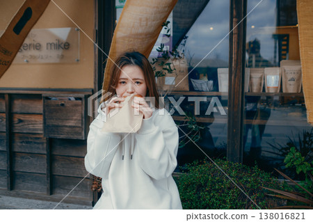 A woman in her 20s enjoying freshly baked bread while strolling around a tourist spot. A woman in her 20s enjoying freshly baked bread while strolling around a tourist spot. 138016821
