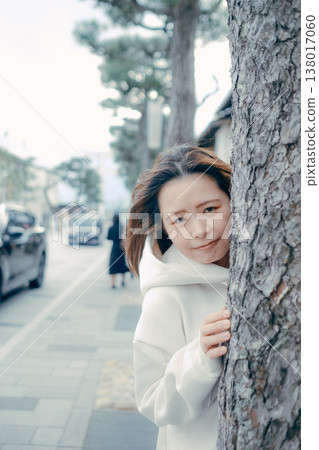 城市裡,一名二十多歲的女子從樹後探出頭來。 城市裡,一名二十多歲的女子從樹後探出頭來。 138017060
