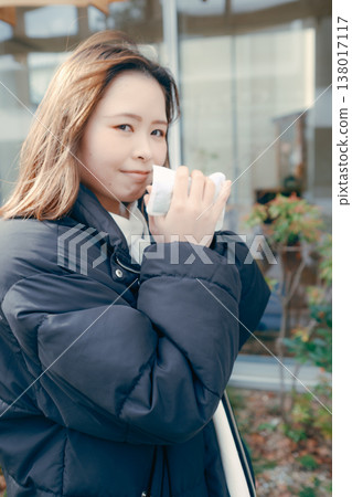A woman in her 20s warms her hands with a hand warmer in winter. 138017117