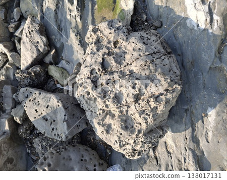 Natural coastal rock forms with textured and weathered boulders by the shore offer a striking look at how the sea shapes stone over time 138017131