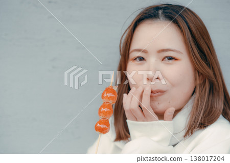 A portrait of a woman in her 20s enjoying a strawberry candy at a tourist spot. A portrait of a woman in her 20s enjoying a strawberry candy at a tourist spot. 138017204