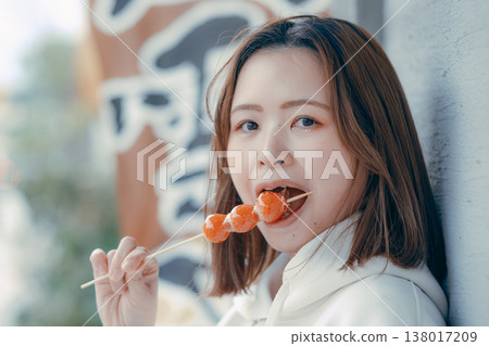 A portrait of a woman in her 20s enjoying a strawberry candy at a tourist spot. A portrait of a woman in her 20s enjoying a strawberry candy at a tourist spot. 138017209