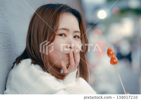 一位二十多歲的女性在旅遊景點享用草莓糖的肖像。 138017210