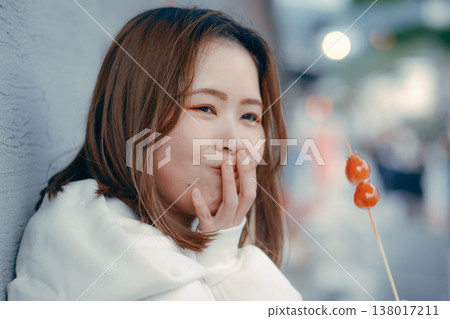 一位二十多歲的女性在旅遊景點享用草莓糖的肖像。 一位二十多歲的女性在旅遊景點享用草莓糖的肖像。 138017211