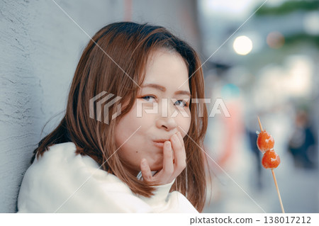 A portrait of a woman in her 20s enjoying a strawberry candy at a tourist spot. A portrait of a woman in her 20s enjoying a strawberry candy at a tourist spot. 138017212