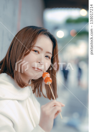 一位二十多歲的女性在旅遊景點享用草莓糖的肖像。 138017214