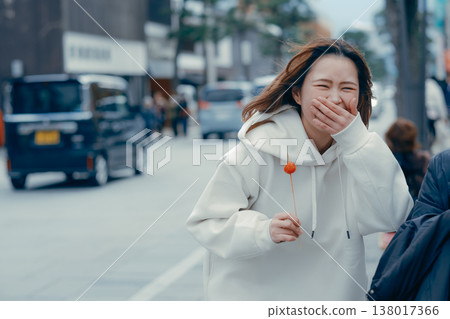 A scene of a woman in her 20s enjoying street food in a tourist area. A scene of a woman in her 20s enjoying street food in a tourist area. 138017366